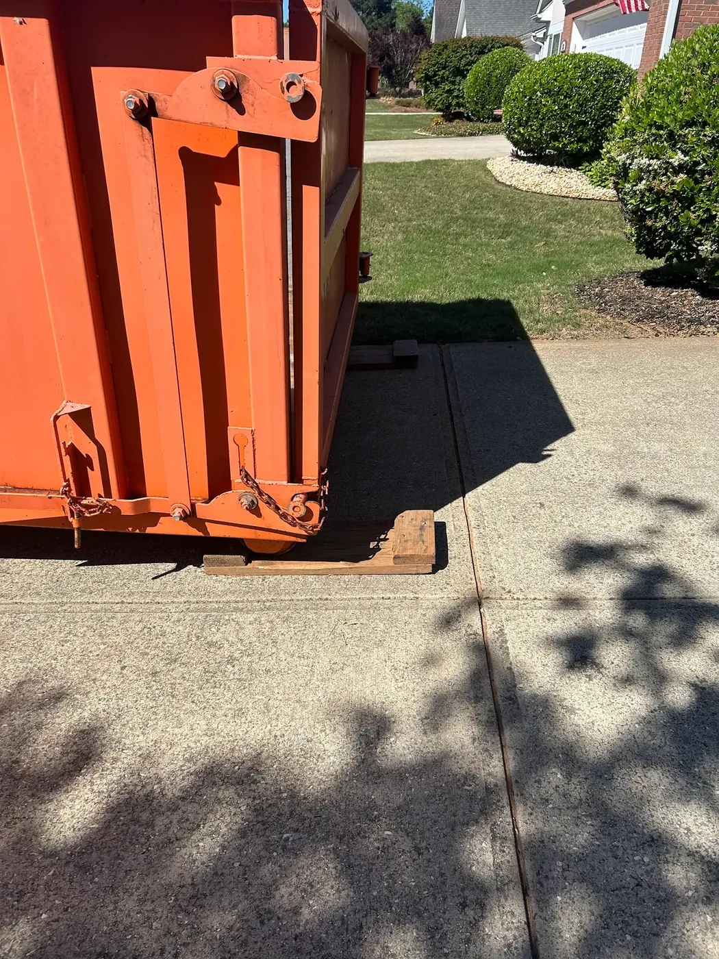 Roll-Off Express dumpster placed on protective wood boards on a concrete driveway